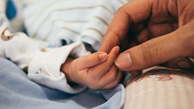 Erwachsene Hand hält Hand eines Babys