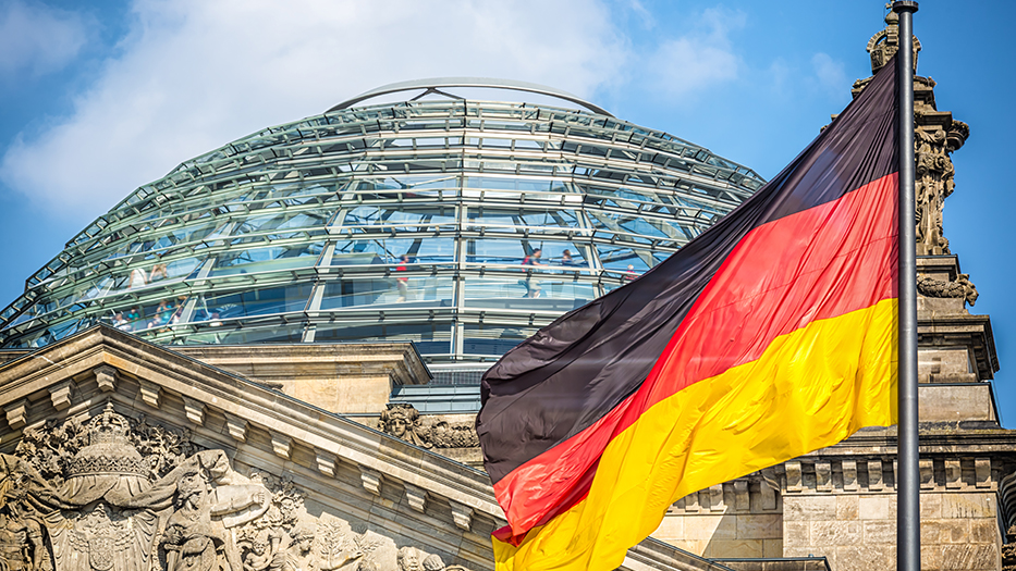 Kupel des Reichstags in Berlin mit der deutschen Flagge im Vordergrund