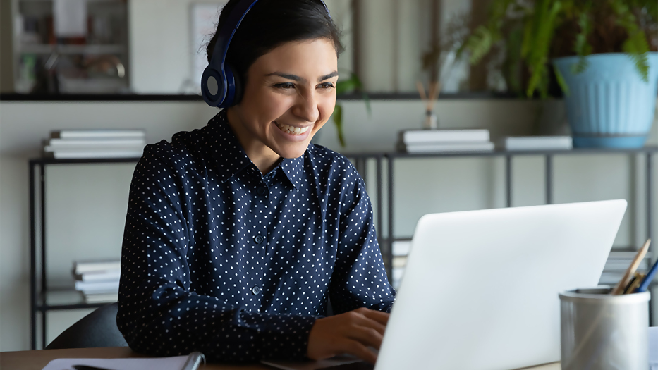 Das Foto zeigt eine junge Frau mit Laptop und kabellosen Kopfhörern